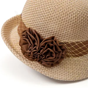 Close-up of beige straw sun hat featuring brown ribbon and elegant floral detail