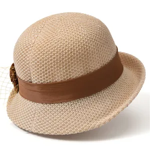 Detail of elegant straw sun hat featuring a wide brown ribbon and floral mesh decoration