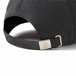 Détail de la casquette noire en coton montrant la sangle réglable et la boucle J5 en métal