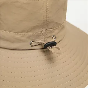Close-up of khaki bucket hat featuring adjustable drawstring with metal eyelet and stitching
