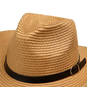 Close-up of straw sun hat featuring woven texture with black leather band and silver buckle