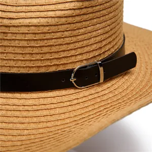 Detail of straw hat texture with black leather band and silver buckle on white background