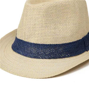 Close-up of beige straw fedora featuring a wide navy blue woven band and fine texture