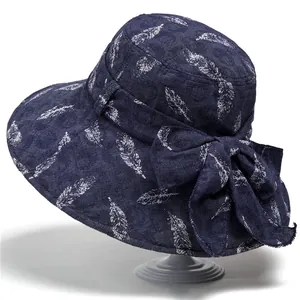 Navy blue wide brim sun hat with white feather pattern and a large side bow detail