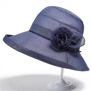 Detail of elegant dark blue sun hat with layered floral decoration and mesh texture