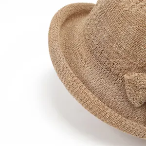 Detail of a brown woven sun hat featuring a fine crochet texture and a side bow knot