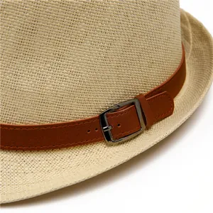 Close-up of beige straw jazz hat with brown leather band and metal buckle detail