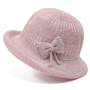 Close-up of pink knitted bucket hat showing textured fabric and side bow detail