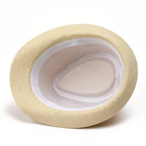 Detailed interior of beige straw fedora hat featuring white sweatband and mesh lining