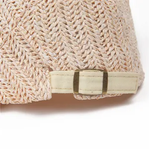 Detailed close-up of woven paper straw texture with vintage bronze metal buckle on sun hat