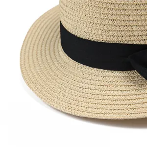 Vista detallada de la textura de paja tejida con cinta negra y lazo en un sombrero boatero