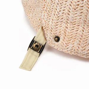 Detailed macro view of the straw hat's canvas strap and vintage bronze metal buckle