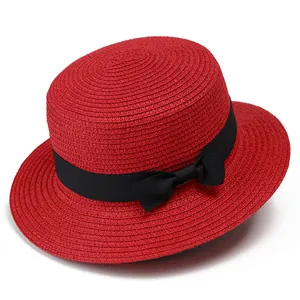 Detalle de sombrero de paja rojo con parte superior plana, cinta negra y lazo elegante
