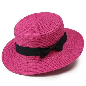 Detalle de sombrero de paja rosa fucsia con cinta de grosgrain negra y un lazo fino