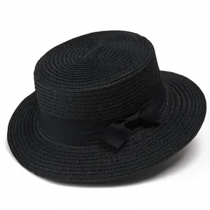 Detalle de sombrero de paja negro con cinta de satén a juego y adorno de lazo