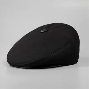 Detailed top view of black wool blend flat cap with classic crown button and warm texture