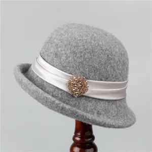 Detail of grey wool cloche hat with pink satin ribbon and beaded vintage brooch