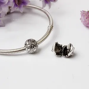 Vue macro du charm étoile de mer en argent sur bracelet serpent et fleurs séchées