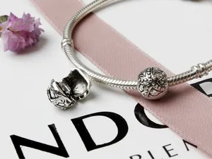 Vue macro d'un charm étoile de mer argentée et perle gravée sur bracelet maille serpent