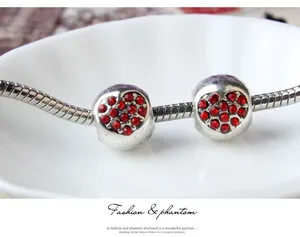 Détail de perles argentées en forme de cœur avec strass rouges sur chaîne serpent