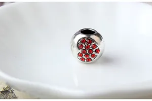 Vue macro d'une perle en argent avec cœur en strass rouge pour la création de bijoux DIY
