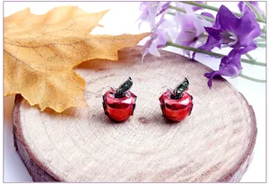 Detalle macro de dijes de manzana roja con acabado esmaltado y hojas verdes brillantes
