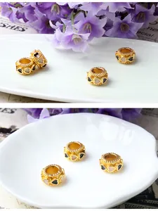 Détail d'une perle cylindrique dorée avec émail en cœur pour création de bijoux DIY