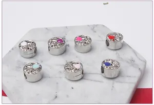 Detailed view of silver beads with colorful enamel hearts and crystals on marble surface