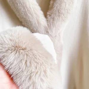 Detailed view of plush faux rabbit fur cuffs on a knit poncho cloak in cream beige color