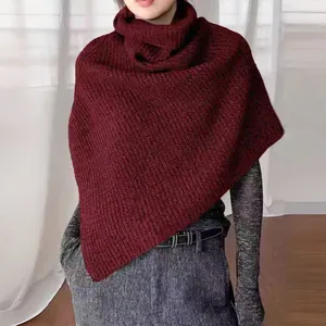 Detail of burgundy high neck knitted poncho showing thick vertical texture and warm draping