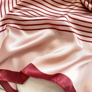 Nahaufnahme des rosa Satin-Vierecktuchs mit roten Streifen und feinen Stickkanten