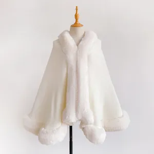 Detailed close-up of white knitted poncho with thick faux fur trim on a mannequin stand