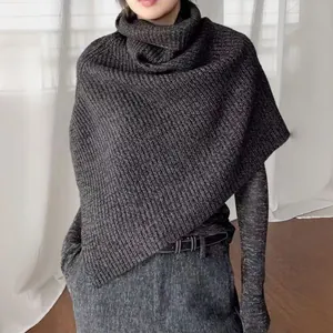 Detail of dark grey knit poncho featuring high collar design and thick ribbed texture