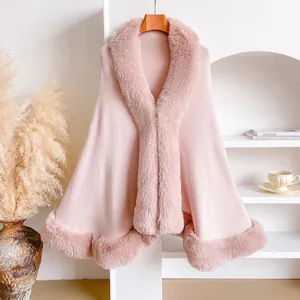 Detail of pink wool knit poncho featuring thick faux rabbit fur trim on collar and hem