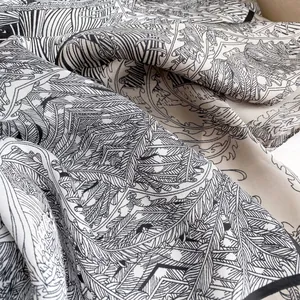 Macro detail of silk square scarf featuring tropical palm leaf prints and botanical patterns
