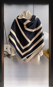Close-up of double-sided cashmere-like scarf with geometric stripes and fringe detail