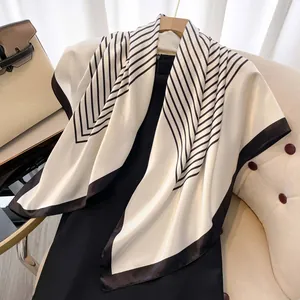 Detail des eleganten cremefarbenen Seidenschals mit schwarzen Streifen und hochwertigem Saum