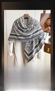Detail of leopard print cashmere scarf with fringe hanging on a white coat