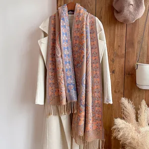 Détail d'une écharpe vintage à motif cachemire et franges, drapée sur un manteau en laine