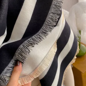 Close-up of soft black and white striped scarf fabric with delicate tassel fringe detail