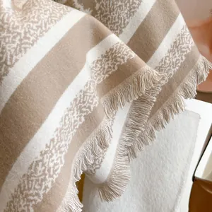Detailed macro view of soft cream and khaki striped cashmere scarf with elegant fringe trim