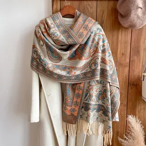 Détail du châle cachemire vintage à motifs paisley et franges sur manteau blanc
