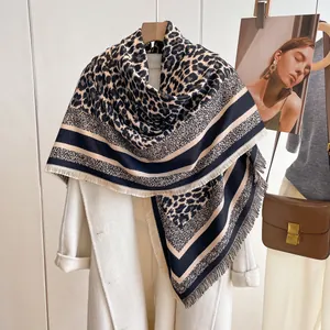 Detail of leopard print cashmere scarf with tassel edges on a white wool coat