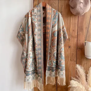 Détail d'un châle ethnique à motif paisley avec franges sur un fond de porte en bois