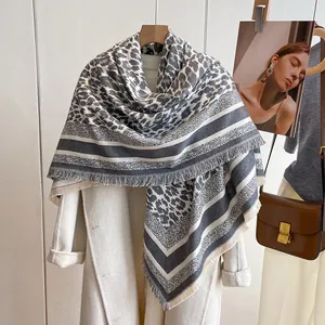 Detail of leopard print cashmere scarf with frayed edges styled on a white coat