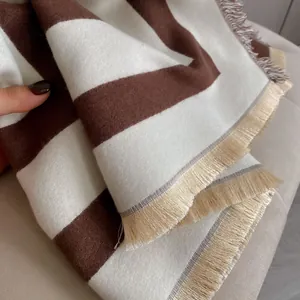 Detailed view of striped cashmere-like shawl with thick texture and tassel edge decor