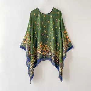 Détail d'un châle poncho vert foncé ample avec imprimé oiseau naturel et bords bleus