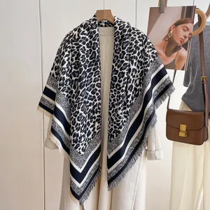 Close-up of leopard print scarf with tassel edges on a beige coat as a warm shawl