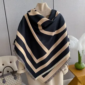 Detail of fringe edges on a thick geometric black and beige shawl over an overcoat