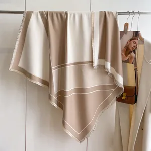 Detalle de la elegante bufanda geométrica beige y blanca con flecos y suave textura de punto